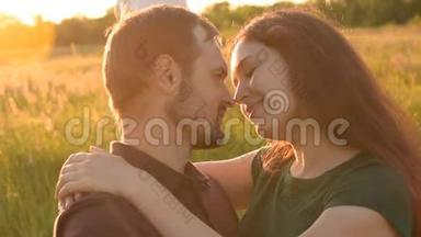 情侣们在日落时在公园里散步时互相摸`鼻子。